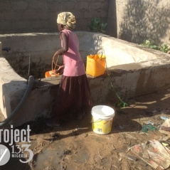 IDP child fetches water from local unsanitary well